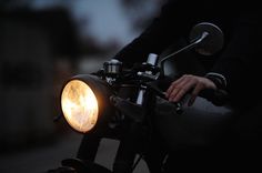 a close up of a person riding a motorcycle with a light on the handlebars