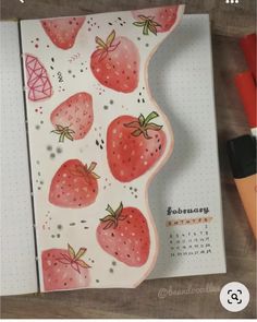 an open notebook with strawberries on it next to markers and marker pens, along with a calendar