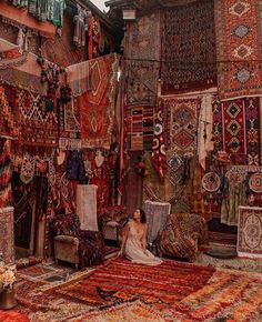 a woman sitting in front of rugs and carpets