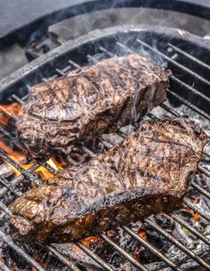 two steaks are cooking on the grill