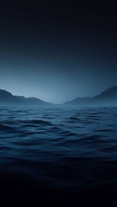 an ocean with mountains in the distance at night