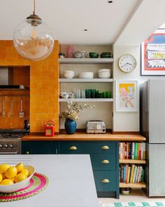 a bowl of lemons sits on the counter in this modern kitchen with orange brick walls