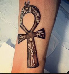 an egyptian cross tattoo on the wrist with an angel and an eye in the center