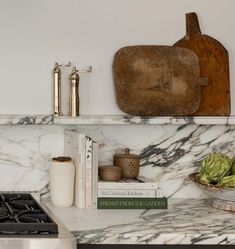 a kitchen with marble counter tops and books on the shelf above it is a wooden cutting board