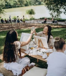 a group of women sitting around a wooden table with paintings on it's sides