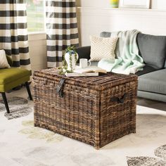 a wicker trunk sitting on top of a rug in front of a gray couch