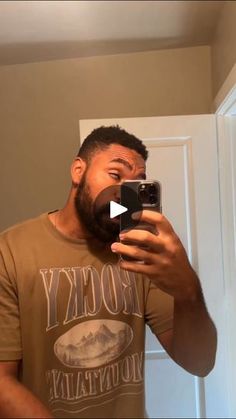 a man taking a selfie in front of a mirror with his cell phone and wearing a rocky mountain t - shirt