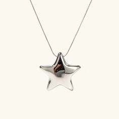 The Stellar Charm Necklace is a playful yet sophisticated piece that radiates charm. Featuring a lustrous star-shaped pendant in your choice of gold or silver, this necklace adds a touch of whimsy to any outfit. Crafted with a sleek, high-shine finish, it’s perfect for everyday wear or special occasions. Hypoallergenic and designed for lasting brilliance, it’s a timeless addition to your jewelry collection.Composition:High-Quality Stainless Steel-Plated 18k Gold.Water, Sweat, and Heat Resistant. (No discoloration, No Tarnishing).Hypoallergenic Skin-Friendly.Comes in an eco-friendly package.Measurement:Length: 16 InchesExtension: 2 InchesPendant Height: 34 mmWeight: 9 g Silver Star-shaped Charm Necklaces For Party, Silver Star Charm Necklaces For Party, Trendy Star Charm Pendant Jewelry, Party Star Charm Necklaces, Trendy Silver Star Necklace, Modern Star Charm Jewelry As A Gift, Sterling Silver Party Jewelry With Star Charm, Modern Star Charm Jewelry Gift, Elegant Silver Star Charm Necklaces