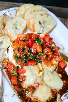 a white plate topped with meat covered in sauce and cheese next to garlic bread slices