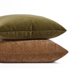 two pillows stacked on top of each other, one brown and the other light green