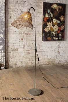 a floor lamp with a metal shade on it in front of a white brick wall