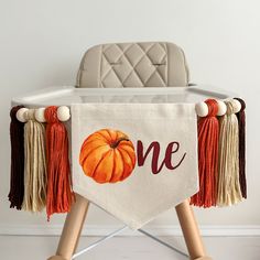 a baby's chair with a one sign on it and tassels hanging from the legs