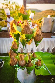 there are many flowers in the vases on the table with people behind them at an outdoor event