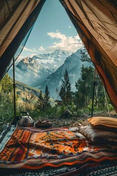 an open tent with mountains in the background and a blanket on the ground next to it