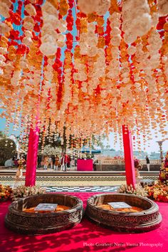 an outdoor ceremony with red and orange decorations hanging from the ceiling, decorated with flowers