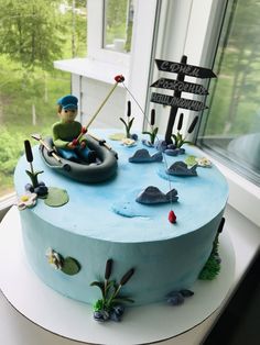 a birthday cake with a boy in a boat on the water and signs pointing to different locations