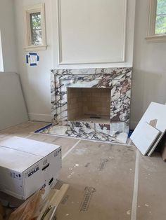 an empty room with a fireplace in the middle and boxes on the floor next to it