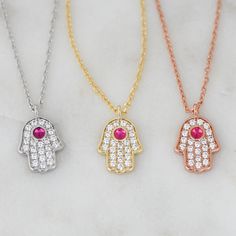 "The Hamsa is said to bring its owner happiness, luck, health, and good fortune. Basically, you NEED this in your life! Super cute Hamsa featuring a ruby stone. Very dainty and delicate, perfect for stacking or wearing it on its on for protection. - - - D E T A I L S - - - * Made of 925 Sterling Silver * THICK plating of 14k Gold, Rose Gold or Rhodium * Hamsa charm measures 11mm x 8mm * Chain Measures 16\" + 3\" Extension Chain * Made of highest grade CZs for an authentic diamond look Made with Spiritual Good Luck Charm Necklaces, Good Luck Charms Pendant Necklace, Spiritual Charm Necklaces For Good Luck, Amulet Charm Necklaces With Adjustable Chain For Gift, Amulet Charm Necklace With Adjustable Chain As Gift, Amulet Style Charm Necklace With Adjustable Chain As Gift, Spiritual Good Luck Pendant Necklace, Amulet Style Round Crystal Necklaces For Gifts, Amulet Pendant Necklace As Gift