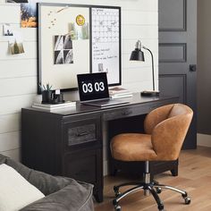 a desk with a clock on it and a chair in front of it, next to a couch