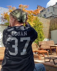 a woman sitting on top of a wooden bench wearing a black shirt with the number 37