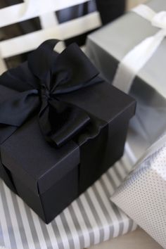 a black gift box sitting on top of a striped table cloth next to a white chair