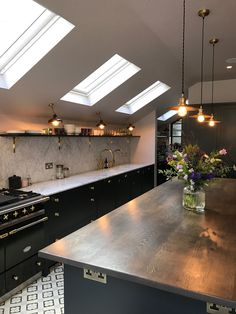 a kitchen with an island and skylights in the ceiling, surrounded by black cabinets