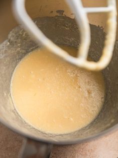 a mixing bowl filled with yellow liquid on top of a counter