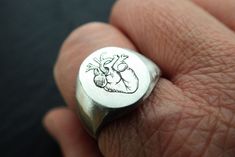 A signet ring with an engraved anatomical heart, a realistic heart, a human heart. It is a ring for both men and women, an engraved ring totally engraved by hand, which makes each ring unique. As it is engraved by hand, it may have some slight variation from the photo. Measurements: Oval top measures 1.6 x 1.3 cm. The heart measures 1.3 x 1 cm. Available in different sizes. If you want to know your ring size you can consult the document attached below, if you have any questions, contact me: http Realist Heart, Heart-shaped Engraved Sterling Silver Ring, Silver Heart Shaped Promise Signet Ring, Symbolic Sterling Silver Heart Ring, Classic Heart-shaped Sterling Silver Engraved Ring, Classic Heart-shaped Engraved Sterling Silver Ring, Sterling Silver Heart Cut Engraved Ring, Silver Heart Shaped Signet Ring Gift, Classic Sterling Silver Heart-shaped Engraved Ring