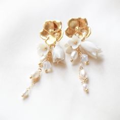 Make a statement on your special day with our gorgeous CALLIE Freshwater Pearl Floral Earrings! Perfect for any modern bride, they combine golden tones with glimmering pearl accents to create an exquisite flowery design. A must-have accessory to complete your look! - PLEASE ALLOW APPROX 10 BUSINESS DAYS FOR COMPLETION BEFORE SHIPPING. - Handcrafted with genuine freshwater pearls and Austrian crystals- Created in my studio in PA- White opal crystals- Freshwater pearls- Polymer clay flowers - Yell Elegant Pearl Earrings With Flower Charm, Elegant Pearl White Jewelry With 3d Flowers, Gold Plated Flower Charm Earrings For Wedding, Elegant Pearl Earrings With 3d Flowers, Gold Feminine Dangle Flower Earrings, Elegant Gold Flower Shaped Pearl Earrings, Elegant Gold Flower Pearl Earrings, Elegant Pearl Bridal Earrings In Flower Shape, Elegant Gold Flower-shaped Pearl Earrings