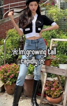 a girl standing in front of some potted plants with her hands on her hips