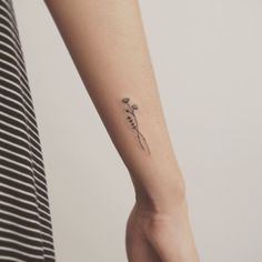 a woman's arm with a small flower tattoo on the left side of her wrist