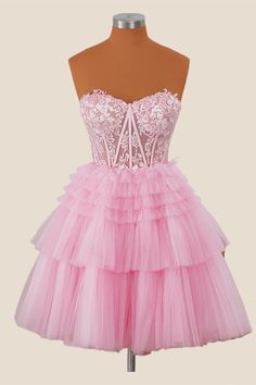 This dress features a lovely pink lace bodice with a sweetheart neckline, a strapless design, and tiered tulle ruffles on the skirt. The A-line silhouette and zip-up back make it easy to wear, and it falls just above the knee for a fun and flirty look. Strapless Sweetheart Neckline Dress With Ruffles For Debutante Ball, Strapless Ruffle Dress With Sweetheart Neckline For Debutante Ball, Party Lace Dress With Ruffles And Sweetheart Neckline, Pink Lace Corset Dress With Fitted Bodice, Sweetheart Neckline Lace Dress With Ruffles For Party, Sleeveless Tulle Corset Dress With Ruffles, Pink Tiered Skirt Prom Dress, Pink Tiered Skirt Dress For Prom, Pink Lace Corset Dress With Corset Back