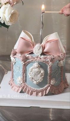 a birthday cake with a candle in the shape of a box and bow on top