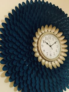 a clock that is on the side of a wall with blue petals and gold accents