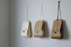 three wooden clocks are hanging on the wall