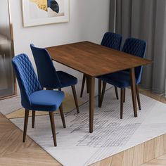 a dining room table with blue chairs and a rug on the floor in front of it