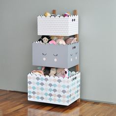 a toy box with stuffed animals in it on top of a wooden floor next to a wall