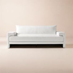 a white couch sitting on top of a floor next to a pink wall with a light colored background