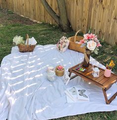 a picnic table with flowers and other items on it in the grass next to a fence