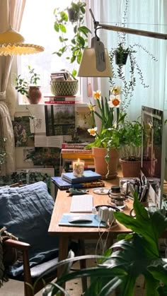 a living room filled with lots of plants next to a desk and chair in front of a window