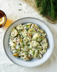 a bowl filled with potato salad next to a glass of lemonade