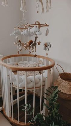 a baby crib with toys hanging from it's sides and a plant in the foreground