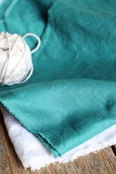 a close up of a piece of cloth on a wooden surface with a ball of yarn