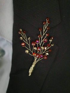 a man wearing a black suit with a red and gold brooch