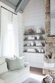 a living room filled with white furniture and lots of bookshelves next to a window