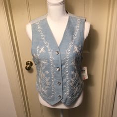 100% Cotton Shell With 100% Polyester Lining. Front Is Light Colored Denim With Beautiful White Embroidery And Pearlized Buttons. Back Is Blue And White Denim Stripes With Decorative Lower Back Belt Buckle That Can Be Adjusted. Size Small. Extra Buttons Included. Pet / Smoke Free Environment. Thanks For Shopping New And Like New! Casual White Cotton Denim Top, Casual Embroidered Denim Vest For Spring, White Cotton Denim Top For Summer, White Fitted Denim Vest, White Denim Top For Spring, White Casual Denim Top For Spring, Summer Embroidered Blue Denim Vest, Blue Embroidered Denim Vest, Embroidered Blue Denim Vest For Summer