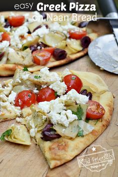 two homemade greek pizzas with tomatoes, olives and feta cheese on them