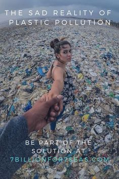 a woman holding the hand of a man on top of a beach covered in trash