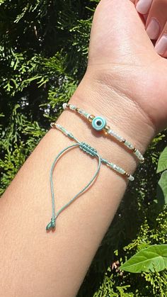 a woman's arm with two bracelets and an evil eye charm on it