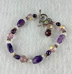 Silver tone with 4 amethyst beads, 5 purple pearls and pinks and clear crystals with aurora borealis. Bracelet is 8 inches long with 2 dangles by the toggle Spiritual Purple Crystal Bracelet With Spacer Beads, Elegant Purple Bracelets With Colorful Beads, Elegant Purple Beaded Crystal Bracelet, Spiritual Purple Beaded Charm Bracelet, Elegant Purple Jewelry With Multi-colored Beads, Adjustable Hand-strung Purple Crystal Bracelet, Elegant Hand-strung Amethyst Beaded Bracelets, Purple Pearl, Hippie Bracelets